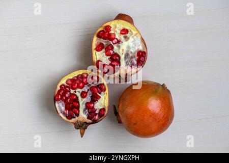 Ein ganzer Granatapfel und anderthalb auf einer hellen Holzoberfläche. Draufsicht. Stockfoto