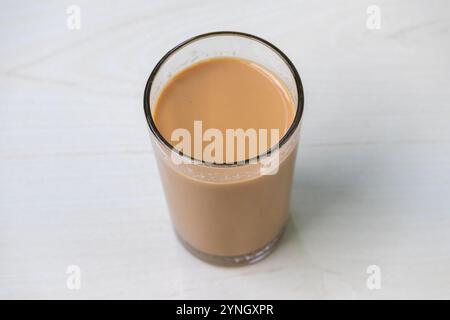 Ein Glas heißer Milchtee (dudh cha) auf einer hellen Holzoberfläche. Stockfoto