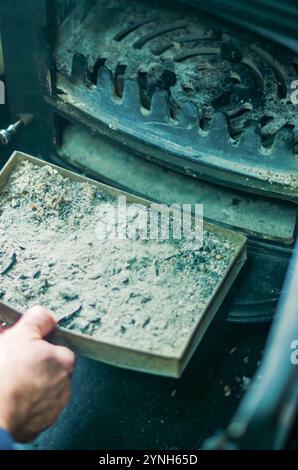 Ein Mann, der einen Pelletofen mit einer Bürste reinigt. Wartungskonzept. Hochwertige Fotos Stockfoto