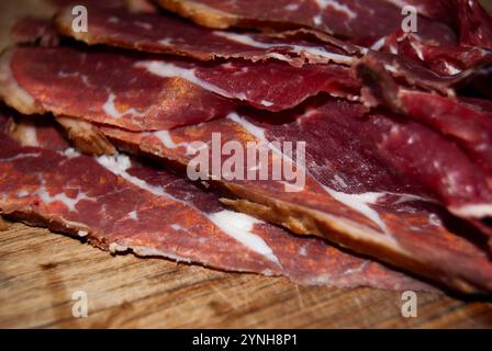 Eine detaillierte Aufnahme von getrocknetem Rindfleisch auf einem Schneidebrett, die seine reichhaltige Textur und Farbe unterstreicht. Stockfoto
