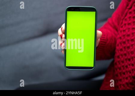 Nahaufnahme einer Frau, die ein Smartphone mit grünem Bildschirm hält Stockfoto