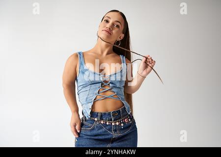 Eine selbstbewusste junge Frau in trendiger Denim-Kleidung posiert anmutig, strahlt Stil und Vielfalt aus. Stockfoto