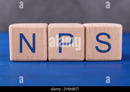 NPS (Net Promoter Score) Abkürzung aus Würfeln auf blauem Holztisch Stockfoto