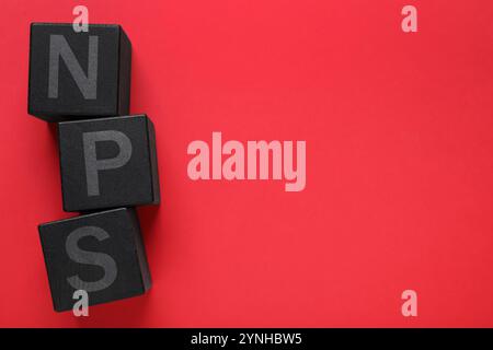 Abkürzung NPS (Net Promoter Score) aus schwarzen Würfeln auf rotem Hintergrund, Draufsicht Stockfoto
