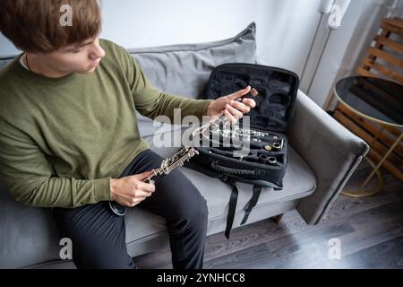 Man Hands legt zerlegte schwarze Klarinette in einen speziellen Fall, inspiziert Teile der Flöte nach dem Spielen Stockfoto