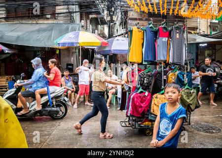 Eine Dame schiebt ihren mobilen Marktstand und verkauft Kleidung in einer typischen Straße im Tondo-Viertel von Manila auf den Philippinen. Stockfoto