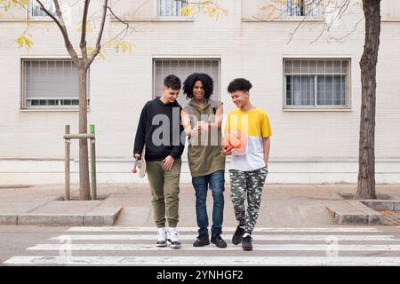 Drei verschiedene Teenager-Freunde, die ein Mobiltelefon suchen Stockfoto