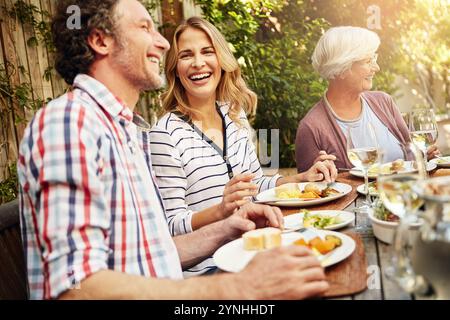 Frau, lachen und Familie mit Essen, zusammen essen und zu Hause Hinterhof mit Lächeln. Thanksgiving, Feier und Leute mit Wein im Urlaub, Festival Stockfoto