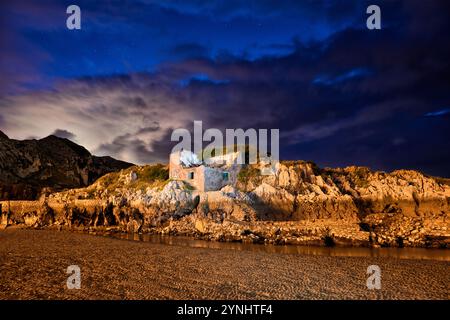 Lange Exposition einer Felsmauer mit antiker Konstruktion in einem kleinen See in der Abenddämmerung mit auffälliger Farbe Stockfoto