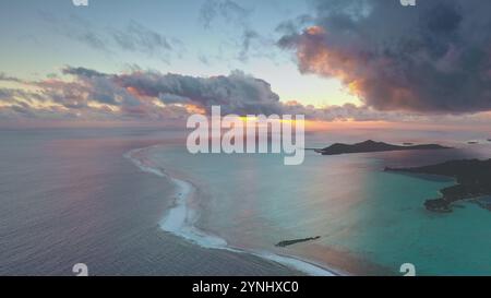 Dramatischer Sonnenuntergangshimmel über der tropischen Insel im Südpazifik. Korallenriffbarriere türkisfarbene Lagune unter farbenfroher Wolkenlandschaft. Panoramablick der Drohne auf Bora Bora - beliebtes Touristenziel Stockfoto