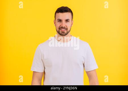 Porträt eines lächelnden Mannes in weißem T-Shirt vor gelbem Hintergrund. Stockfoto