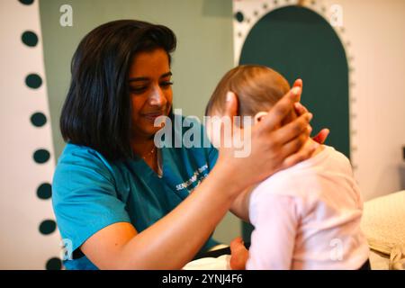 Brindini Senthilkumaran, ein Osteopath in der Region Paris, führt einen Dekompressionstest an der Schädelbasis eines Säuglings durch. Brindini Senthilkumaran ist ein französischer Osteopath, der auf perinatale Pflege und Frauengesundheit spezialisiert ist. Stockfoto