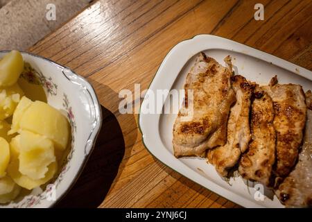 Gegrillte Hähnchenstreifen und gekochte Kartoffeln auf rustikalem Tisch – klassisches Hausgericht Stockfoto