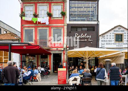 Porto, Portugal - 17. Juli 2024: Touristen essen in Terrassenrestaurants am Fluss Douro im Hafenviertel zu Mittag. Stockfoto