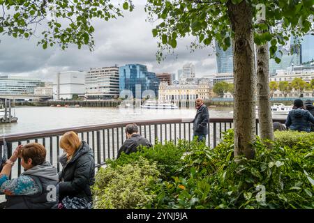 Menschen, die sich am South Bank mit Blick auf die Themse in London in Großbritannien in Europa entspannen. Stockfoto