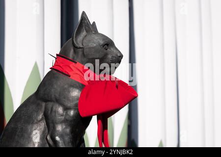 London, Großbritannien. 26. November 2024. Zwei große Katzenskulpturen, die den Eingang zum Greater London House in Mornington Crescent bewachen, sind mit festlichen roten Bögen für die Weihnachtszeit geschmückt. Das Art-Deco-Gebäude, ursprünglich die Carreras Zigarettenfabrik, ist ein Beispiel für die ägyptische Wiedergeburt-Architektur des 20. Jahrhunderts und die Katzen repräsentieren die ägyptische Göttin Bastet. Quelle: Ron Fassbender/Alamy Live News Stockfoto