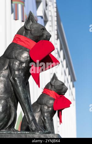 London, Großbritannien. 26. November 2024. Zwei große Katzenskulpturen, die den Eingang zum Greater London House in Mornington Crescent bewachen, sind mit festlichen roten Bögen für die Weihnachtszeit geschmückt. Das Art-Deco-Gebäude, ursprünglich die Carreras Zigarettenfabrik, ist ein Beispiel für die ägyptische Wiedergeburt-Architektur des 20. Jahrhunderts und die Katzen repräsentieren die ägyptische Göttin Bastet. Quelle: Ron Fassbender/Alamy Live News Stockfoto