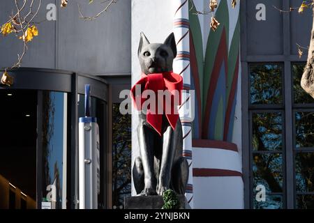 London, Großbritannien. 26. November 2024. Zwei große Katzenskulpturen, die den Eingang zum Greater London House in Mornington Crescent bewachen, sind mit festlichen roten Bögen für die Weihnachtszeit geschmückt. Das Art-Deco-Gebäude, ursprünglich die Carreras Zigarettenfabrik, ist ein Beispiel für die ägyptische Wiedergeburt-Architektur des 20. Jahrhunderts und die Katzen repräsentieren die ägyptische Göttin Bastet. Quelle: Ron Fassbender/Alamy Live News Stockfoto