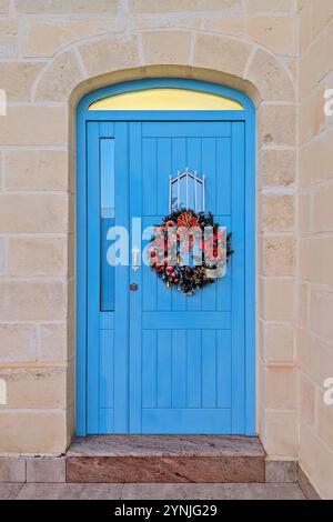 Lebendige blaue Tür mit festlichem Weihnachtskranz Stockfoto