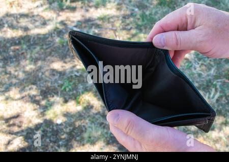 Ein Mann, der leere schwarze Anführer-Partimone in den Händen hält. Die Brieftasche ohne für den Handel. Stockfoto