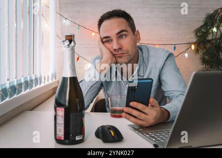 Junger Mann mit Kater nach der Neujahrsparty im Büro. Der Geschäftsmann ist bei der Arbeit müde. Ein betrunkener Mitarbeiter ist nach einer Firmenfeier krank Stockfoto