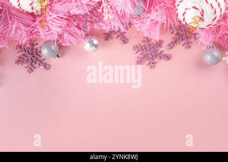 Kitschmas Weihnachtshintergrund mit flauschigen rosa künstlichen Weihnachtsbaumbrunches, rosa festliche Schleife und Dekorationen im trendigen umhüllenden Kitschstil, Stockfoto