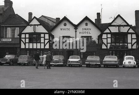 1970er Jahre, historische Autos aus der Zeit, die vor dem historischen alten Public House geparkt wurden, The White Swan Hotel, Rother Street, Stratford upon Avon, England, Großbritannien. Der Weiße Schwan existiert seit 1560. Stockfoto