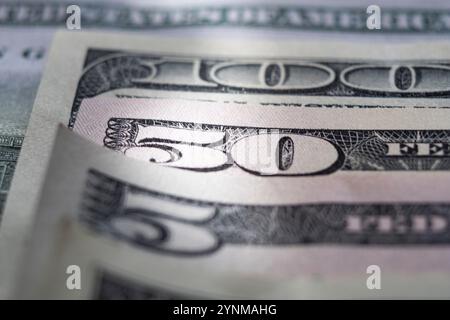 Nahaufnahme einer Makroaufnahme von fünfzig Dollar-Scheinen, die auf 100 Dollar-Scheinen liegen, wodurch ein abstraktes Muster entsteht, das die amerikanische Währung und das Finanzwesen repräsentiert Stockfoto