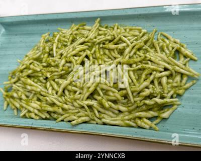 Trofie - eine kurze, dünne, gedrehte Pasta - wird in einer Pesto-Sauce geworfen und in einem Restaurant in Norditalien auf einem Teller serviert. Stockfoto