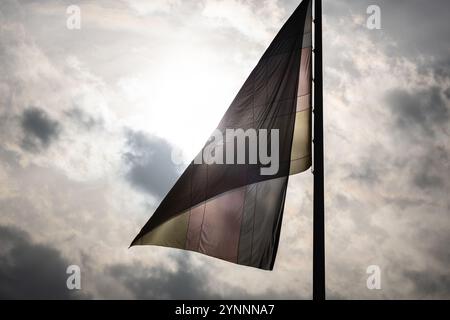 Berlin, Deutschland. November 2024. Eine deutsche Flagge wird von der Sonne am bewölkten Himmel beleuchtet. Quelle: Hannes P. Albert/dpa/Alamy Live News Stockfoto