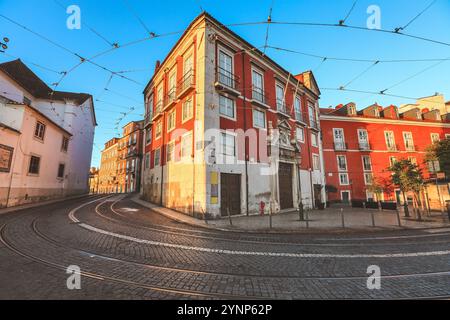 Blick auf die traditionelle alte Straße und farbenfrohe Gebäude am Morgen mit Straßenbahnschienen in Lissabon. Bezirk Alfama. Portugal. Stockfoto