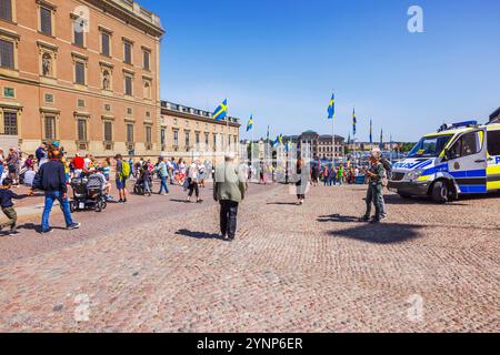 Menschenmassen feiern Schwedens Nationalfeiertag mit schwedischen Fahnen, historischer Architektur und Polizeipräsidenz auf dem Platz. Schweden. Stockholm. Stockfoto