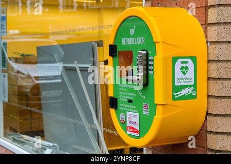 Pontypridd, Wales, Großbritannien - 24. November 2024: Nothilfe-AED-Herz-Wiederstartgeräte in einem verschlossenen Schrank an der Wand eines Ladens im Stadtzentrum von Pontypridd Stockfoto