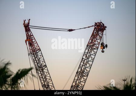 Nahaufnahme eines Baukrans mit sich kreuzenden Auslegern in der Abenddämmerung, Silhouette vor einem klaren Himmel, die die komplizierten Details erfasst Stockfoto