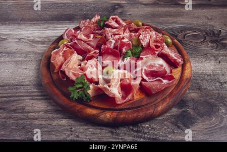Sortiment, Fleischvorspeise in Scheiben, Schinken, Salami und Schinken, mit Oliven, auf einem Holzbrett, Frühstück, Blick von oben, Nahaufnahme, keine Leute Stockfoto