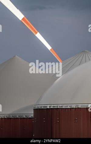 Gasspeicher einer Biogasanlage, Flügel einer Windenergieanlage, das Gas wird aus verschiedener Biomasse erzeugt, der Strom wird in Blockheizwärme erzeugt und Stockfoto