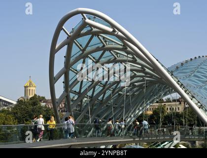 Die gewölbte futuristische Friedensbrücke über den Fluss Kura, Architekt Michele de Lucci, hinter der Heiligen Dreifaltigkeit Kathedrale, auch bekannt als Sameba Kathedrale Stockfoto