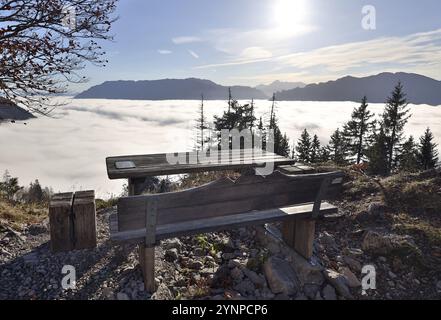 Eine rustikale Holzbank steht auf dem Hochstaufen als Ruheplatz über dem herbstlichen Nebelmeer, Chiemgauer Alpen, Oberbayern, Bayern, Deutschland, Euro Stockfoto