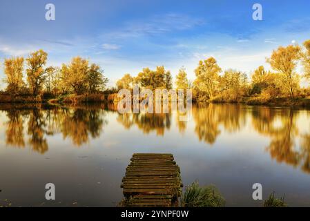 Ein Blick auf eine Anlegestelle im See bei Sonnenaufgang im Wald mit Herbstfarben Stockfoto