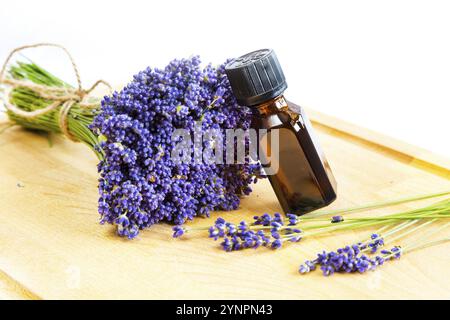 Frische Lavendelblüten und eine Flasche Öl auf Holz- Hintergrund Stockfoto