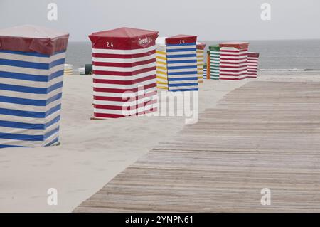 Bunt gestreifte Strandhütten entlang eines Holzstegs, Meerblick, borkum, Nordsee, deutschland Stockfoto