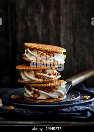 Drei Eis-Sandwiches mit Karamellsauce, karamelisierten Nussstücken, gestapelt auf einem Spachtel in dunkler Holzatmosphäre Stockfoto