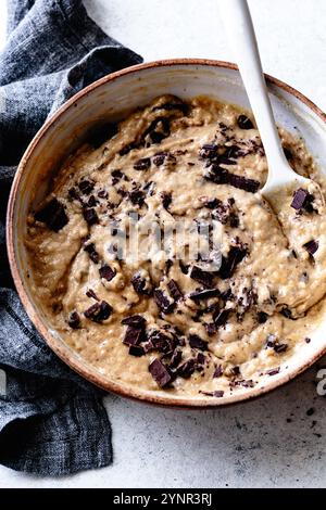Eine Schüssel Keksteig mit Stückchen dunkler Schokolade gemischt, umgeben von einem grauen Küchentuch. Stockfoto