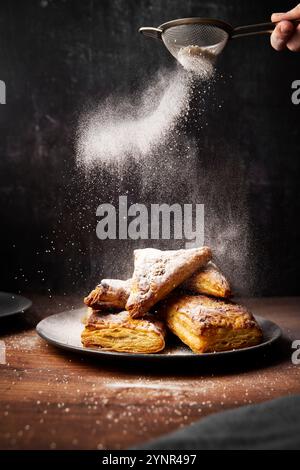 Apfelumschläge mit Puderzucker auf Holzoberfläche Stockfoto