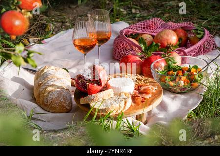 Picknickszene mit Blick auf das Leben mit frischen Granatäpfeln, Walnüssen, Pinienkernen und cremigem Weißkäse auf einem Holzbrett, natürlichem Sonnenlicht-Pomegra Stockfoto