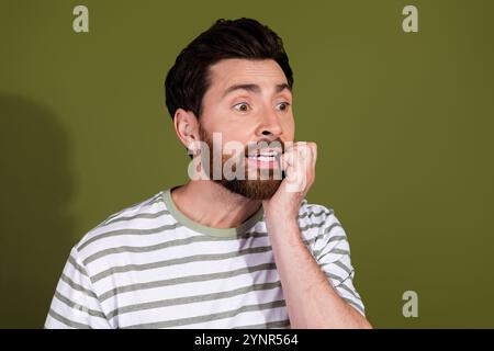 Foto des besorgten nervösen Mannes tragen gestreifte Kleidung beißen Fingernägel leerer Raum isoliert auf khakifarbenem Hintergrund Stockfoto