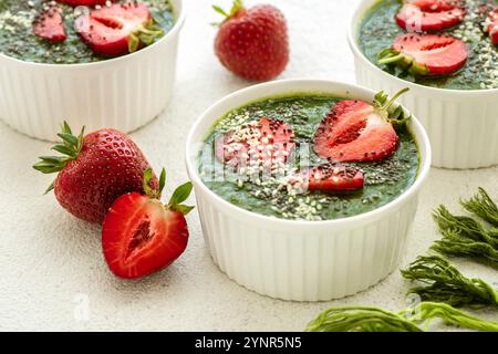 Grüner Smoothie mit Erdbeeren in weißen Schüsseln auf weißem Hintergrund Stockfoto