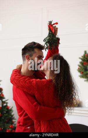 Ein reizendes Paar unter Mistelzweigen im Zimmer, das zu Weihnachten dekoriert war Stockfoto