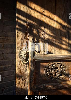 Alter chinesischer Metallklopfer an rustikaler Holztür. Stockfoto