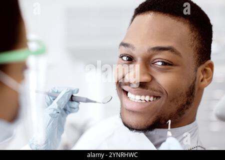 Gutaussehender, Lächelnder Schwarzer, Der Während Der Medizinischen Untersuchung Auf Dem Zahnarztstuhl Sitzt Stockfoto